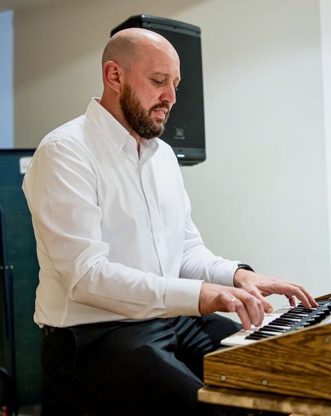 Playing a small keyboard set up on a wooden table.